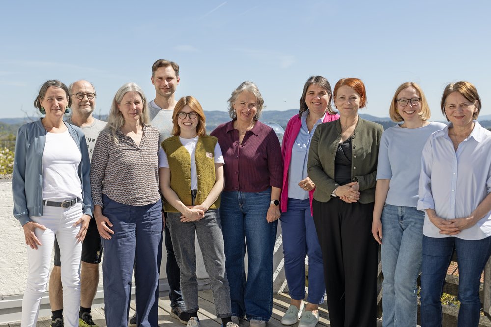 Die Landkreis-Grünen auf der Bezirksversammlung in Perlesreut Zehn Personen posieren für ein Gruppenfoto. Sie stehen auf einer Terrasse in der Sonne.
