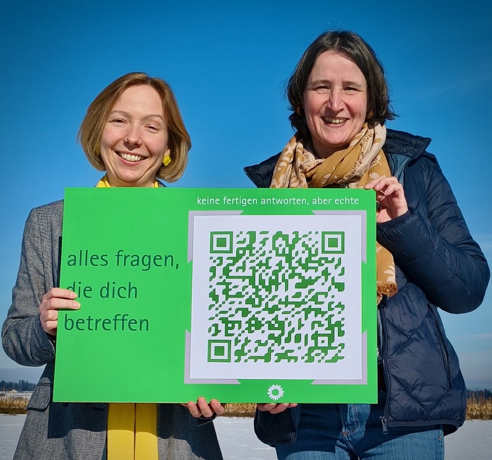 Freuen sich über die Postkarte für ErstwählerInnen: Initiatorin Verena Regner (rechts) und Kreisvorsitzende Claudia Woller (links) Zwei Frauen halten eine Postkarte im XXL-Format in den Händen. Auf der Postkarte steht "alles fragen, die dich betreffen"