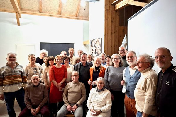 Etwa 30 Personen stehen für ein Gruppenfoto zusammen. Im Vordergrund sitzen drei Personen auf Stühlen.
