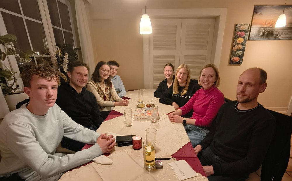 Acht Personen sitzen in einer Pizzeria an einem Tisch.