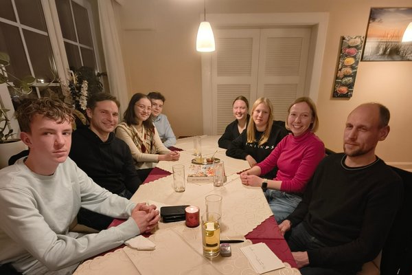 Acht Personen sitzen in einer Pizzeria an einem Tisch.